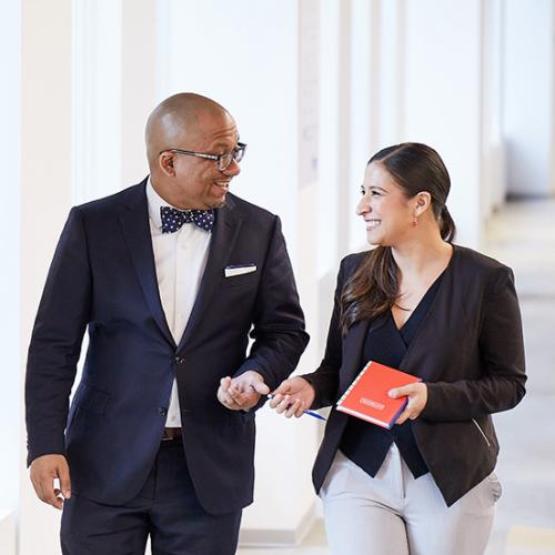 Headshot photo of two Year Up staff members walking down the hallway together