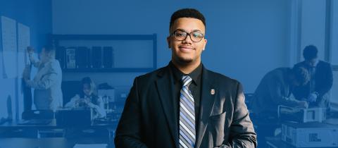 A man in glasses wearing a nice jacket and tie smiling at the camera